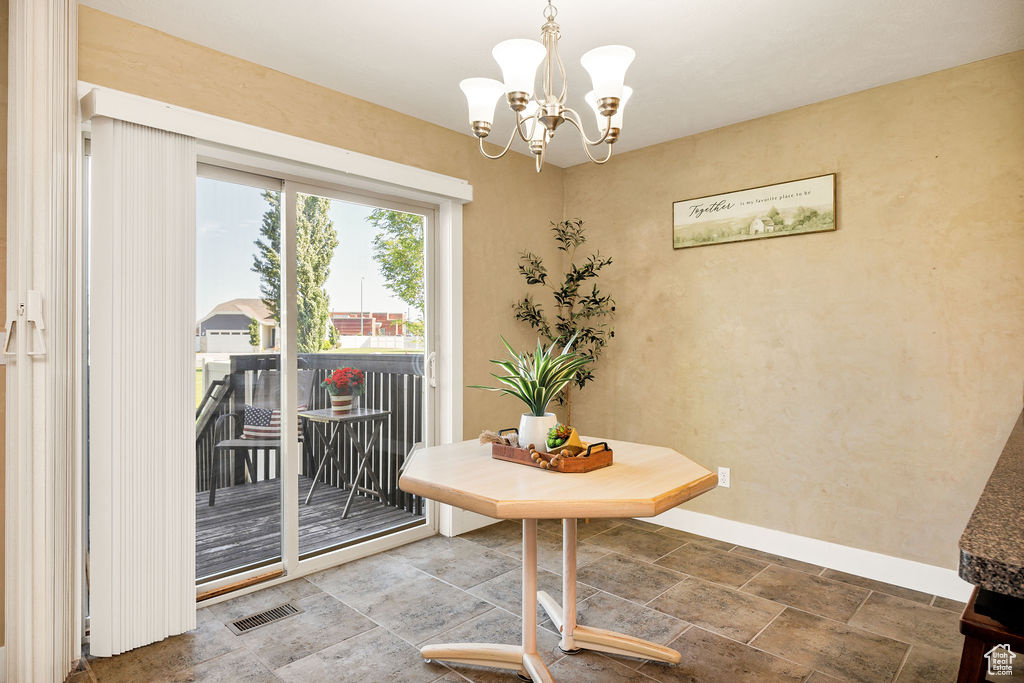 Dining area featuring baseboards, a chandelier, and stone finish floors