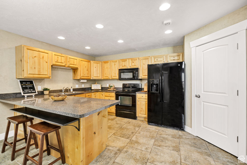 Kitchen with black appliances, light brown cabinets, a peninsula, and recessed lighting