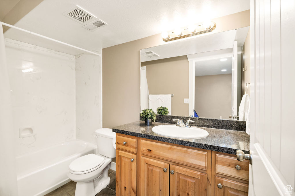 Bathroom featuring vanity, toilet, tile patterned flooring, and  shower combination