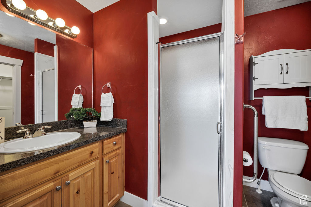 Full bath with vanity, a stall shower, toilet, baseboards, and tile patterned floors