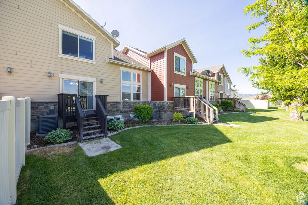 Back of house featuring stone siding and cooling unit