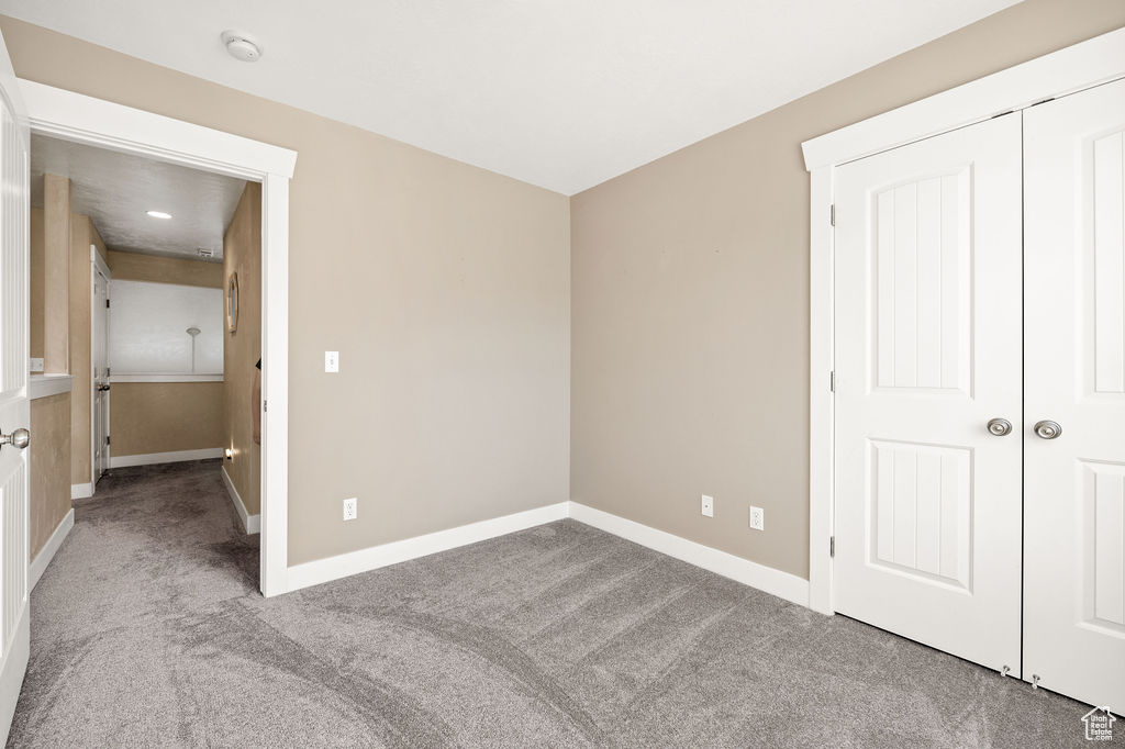 Unfurnished bedroom with carpet flooring and baseboards