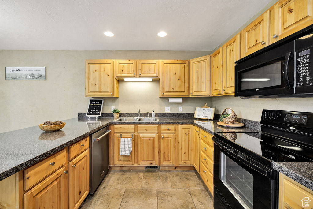 Kitchen with black appliances, a sink, dark countertops, a peninsula, and recessed lighting