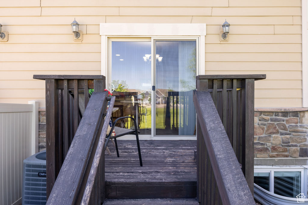 Entrance to property featuring stone siding and central AC unit