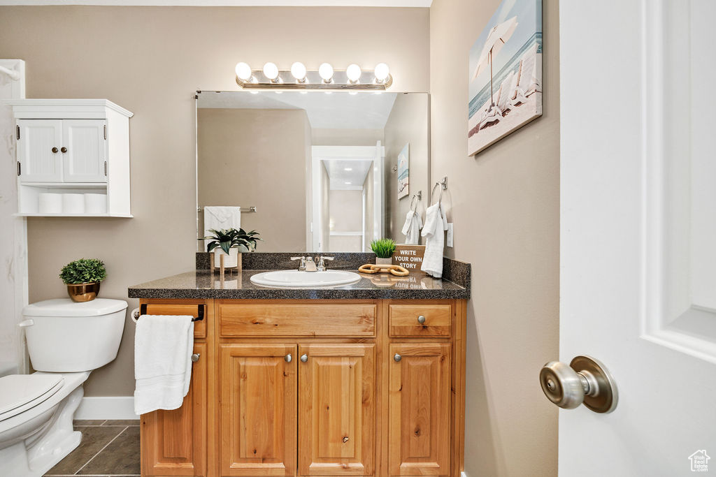 Bathroom featuring vanity, toilet, tile patterned floors, and baseboards