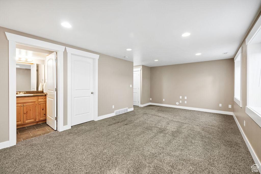 Unfurnished bedroom featuring dark carpet, a sink, recessed lighting, baseboards, and connected bathroom