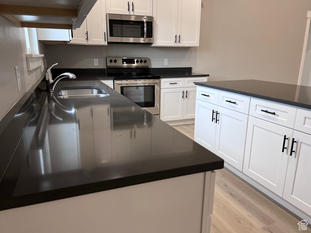 Kitchen with appliances with stainless steel finishes, a sink, and dark countertops