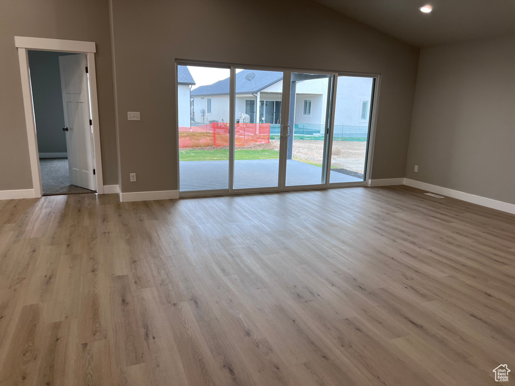 Unfurnished room with wood finished floors, lofted ceiling, baseboards, and recessed lighting