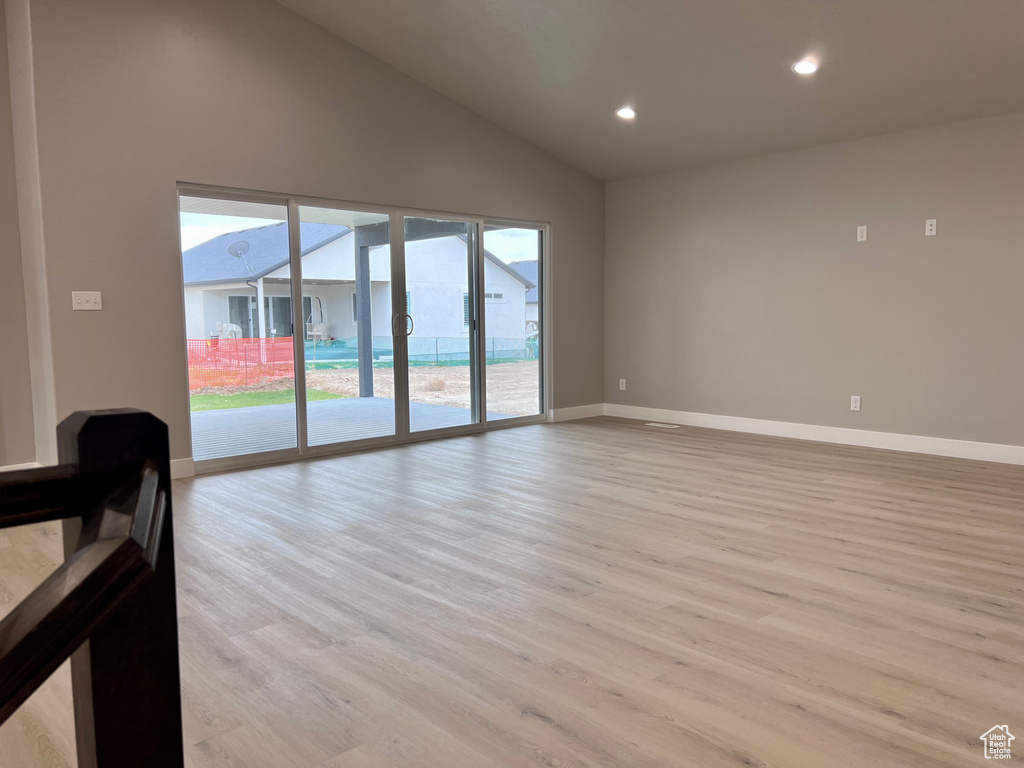 Unfurnished living room with light wood-style floors, baseboards, recessed lighting, and high vaulted ceiling