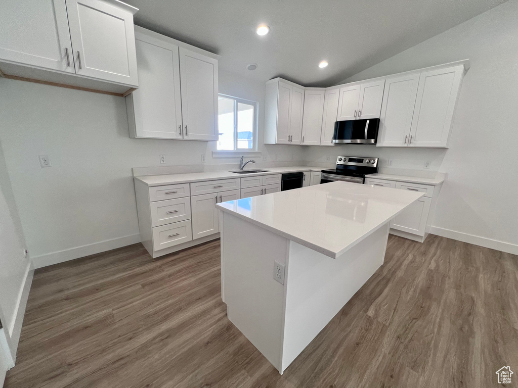 Kitchen featuring stainless steel appliances, a sink, baseboards, white cabinets, and wood finished floors