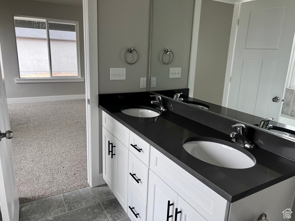 Full bathroom with double vanity and baseboards
