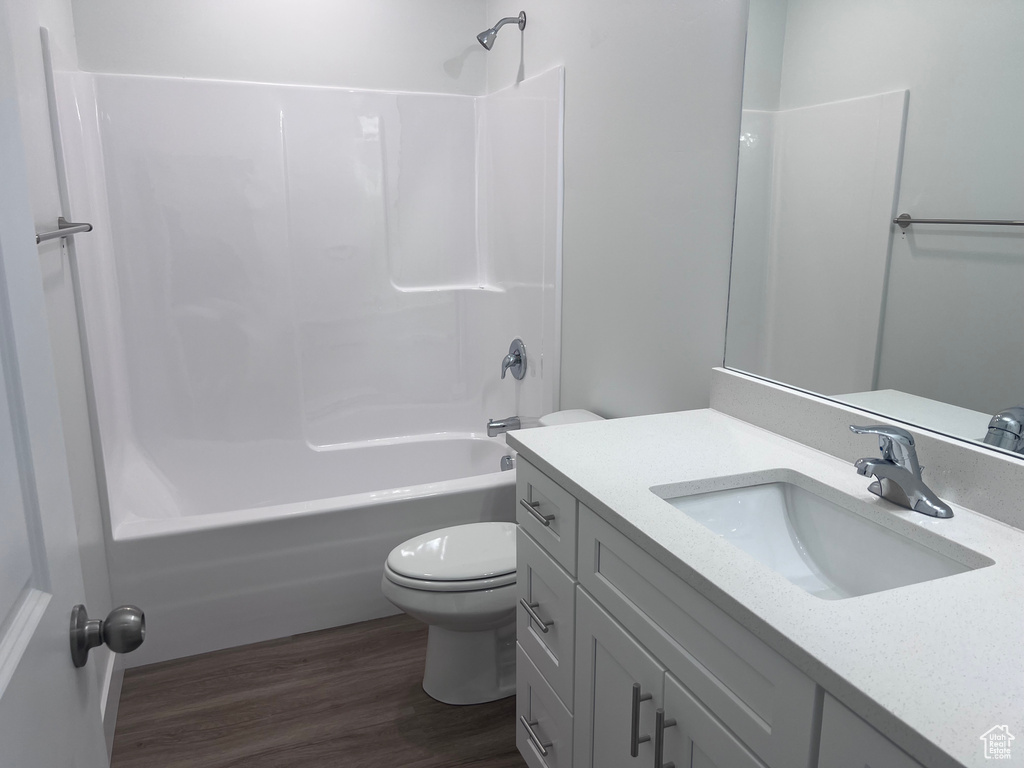 Full bath with toilet, vanity, wood finished floors, and shower / bath combination
