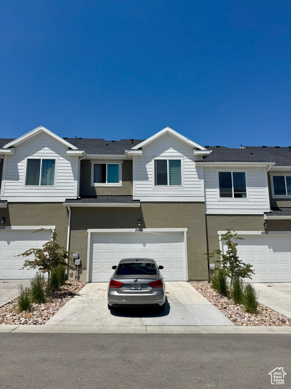 Townhome / multi-family property featuring stucco siding, an attached garage, and driveway