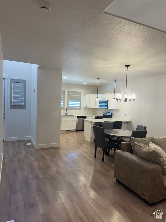 Living area featuring wood finished floors, a textured ceiling, baseboards, and a chandelier