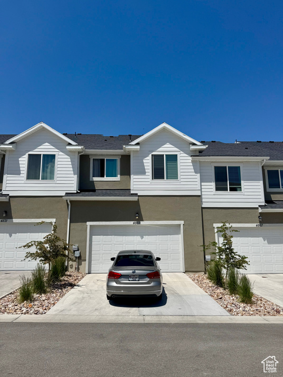Multi unit property with stucco siding, a garage, and concrete driveway
