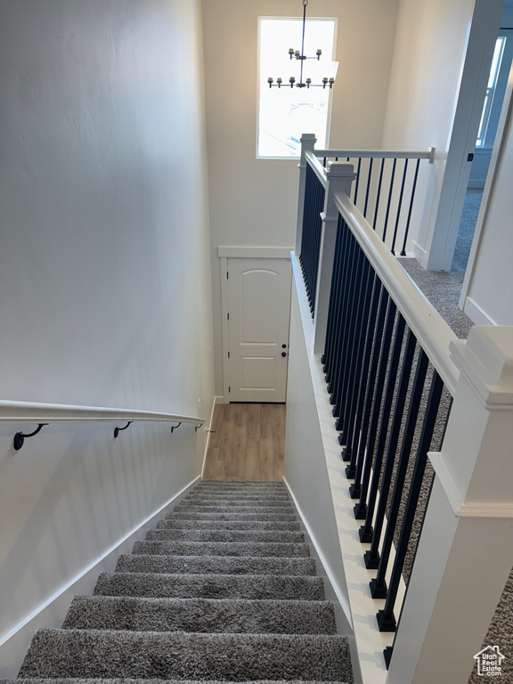 Stairway with a chandelier, a towering ceiling, and wood finished floors