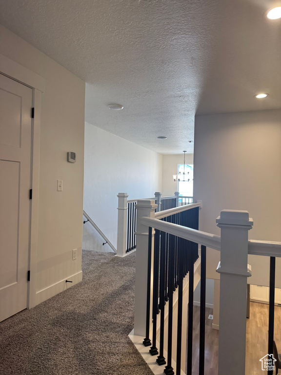 Corridor featuring an upstairs landing, recessed lighting, baseboards, a textured ceiling, and a chandelier