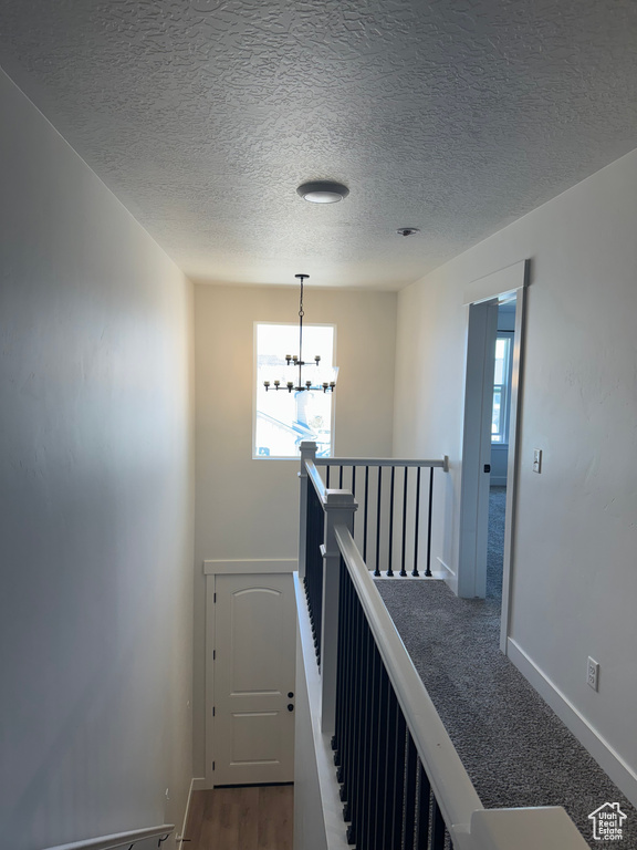 Staircase with a chandelier, baseboards, and a textured ceiling
