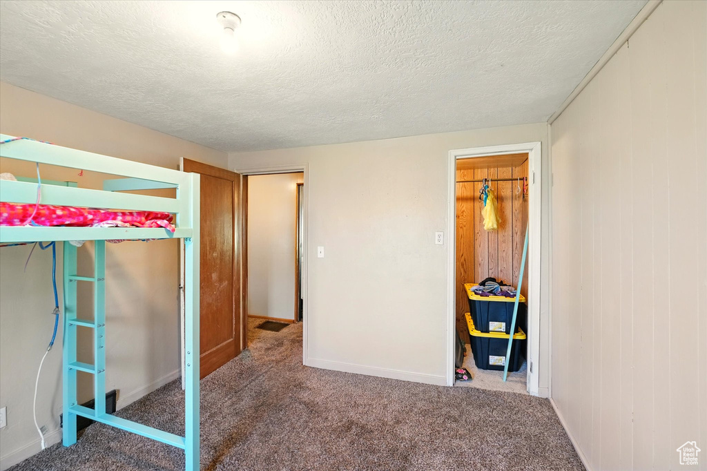 Unfurnished bedroom featuring carpet floors, a textured ceiling, and baseboards