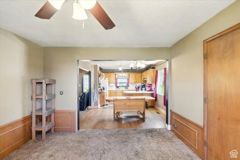 Playroom featuring light colored carpet, a wainscoted wall, ceiling fan, a textured ceiling, and a chandelier