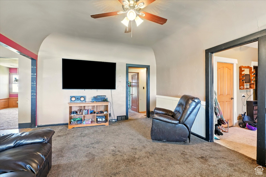 Carpeted living area featuring ceiling fan and vaulted ceiling