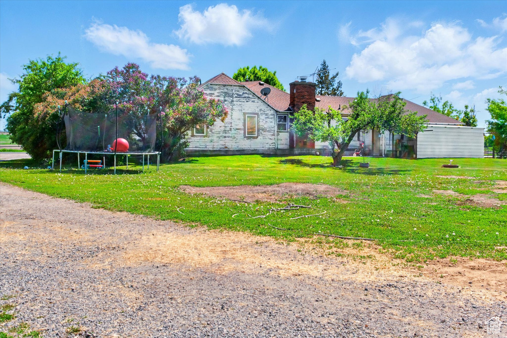 View of front of house with a trampoline, a chimney, and a front lawn