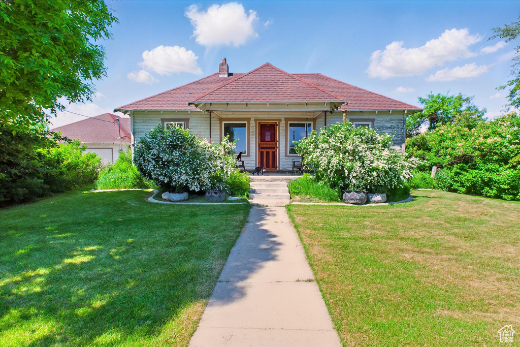 View of front of home featuring a front yard, a porch, and a chimney