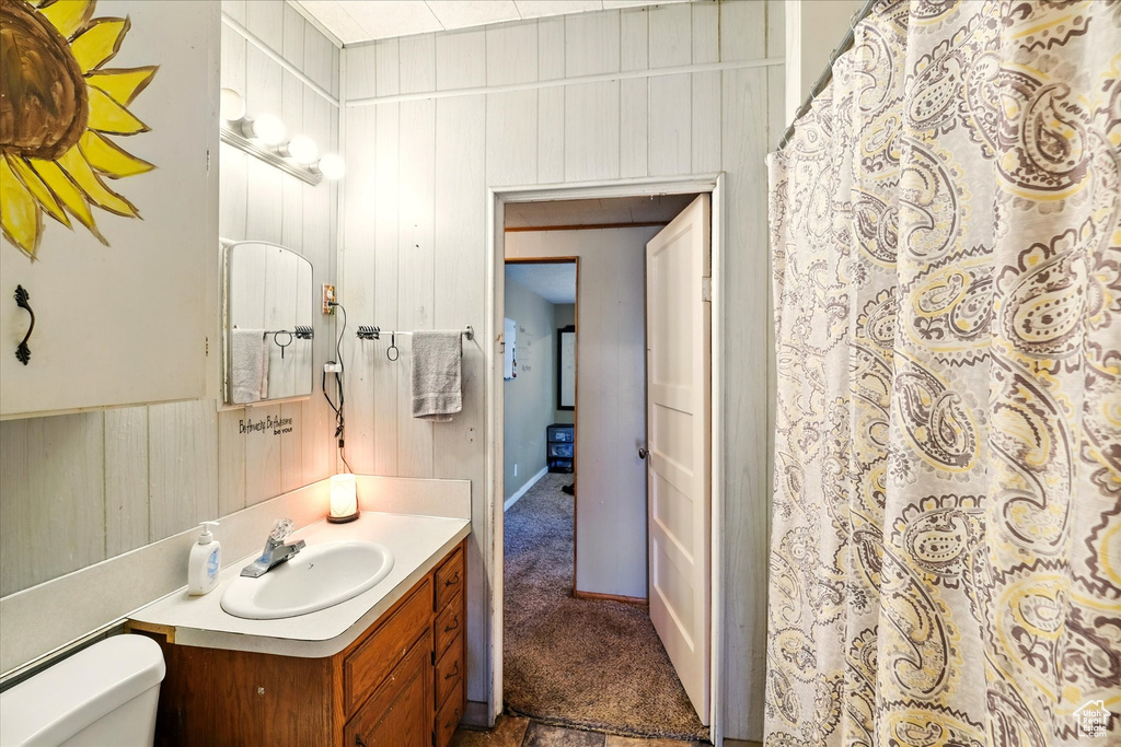 Full bath featuring vanity, toilet, wood walls, and a shower with shower curtain