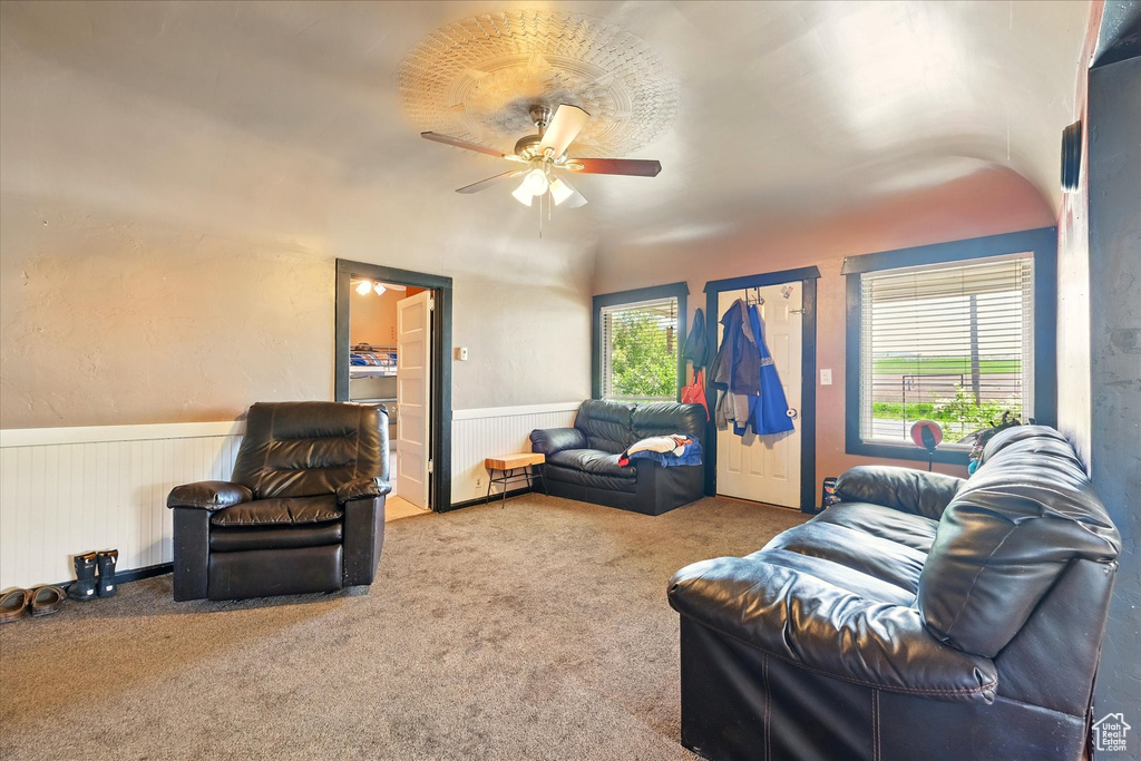 Carpeted living area featuring wainscoting and ceiling fan