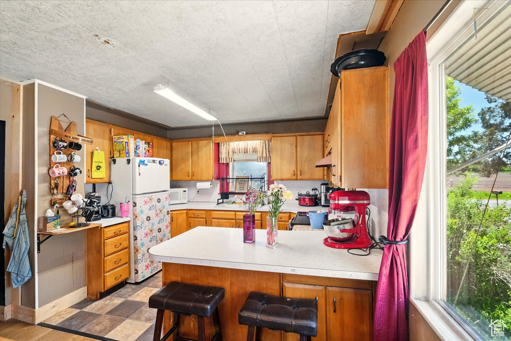 Kitchen featuring white appliances, a peninsula, light countertops, and plenty of natural light
