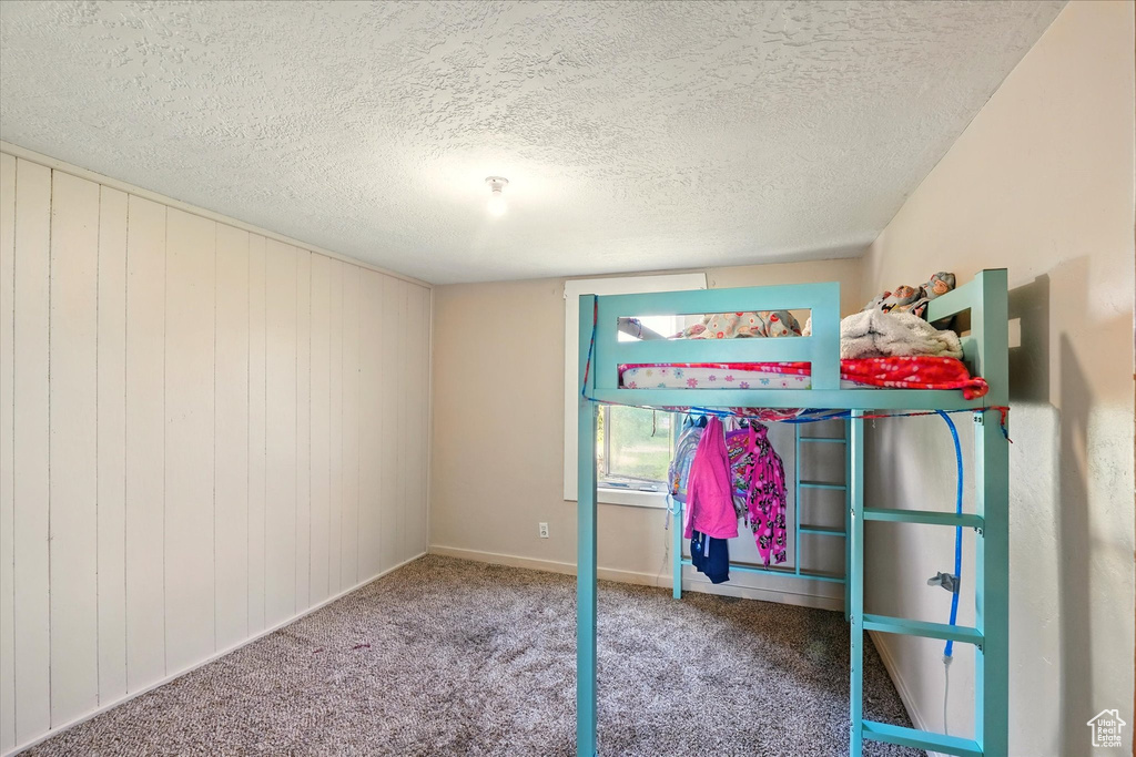 Unfurnished bedroom with a textured ceiling, carpet floors, and baseboards
