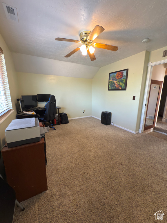 Carpeted office space featuring lofted ceiling, a ceiling fan, and a textured ceiling