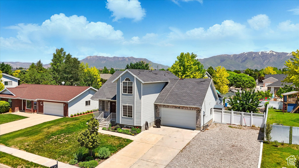 Traditional-style home with an attached garage, a mountain view, concrete driveway, and roof with shingles