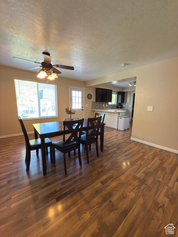 Dining area with a textured ceiling, dark wood-style floors, and ceiling fan