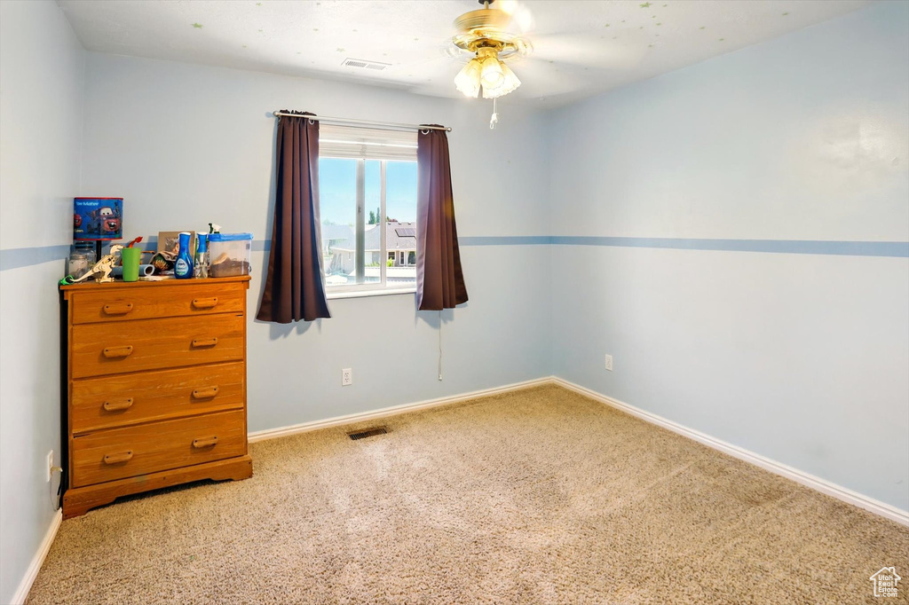 Spare room featuring carpet flooring, ceiling fan, and baseboards