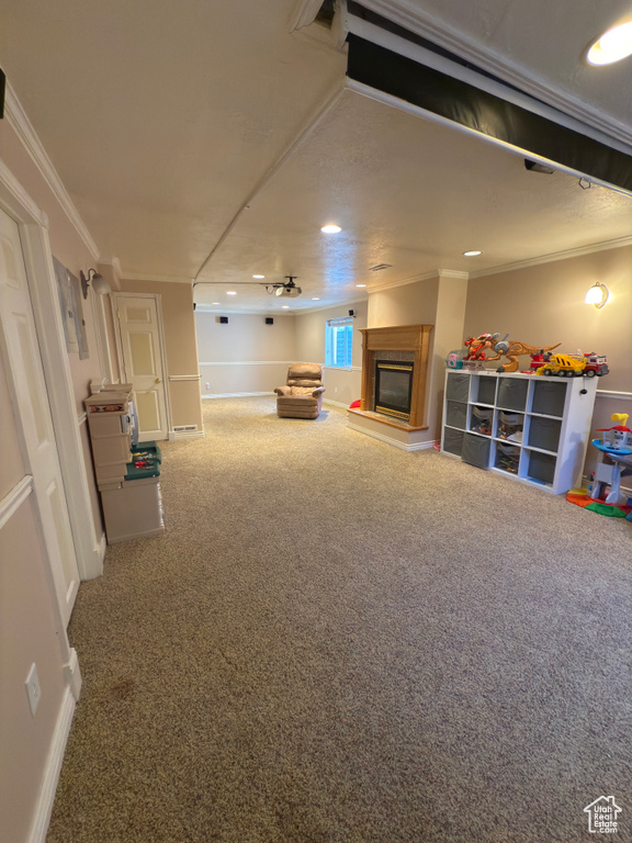 Living room featuring a glass covered fireplace, carpet floors, crown molding, and recessed lighting