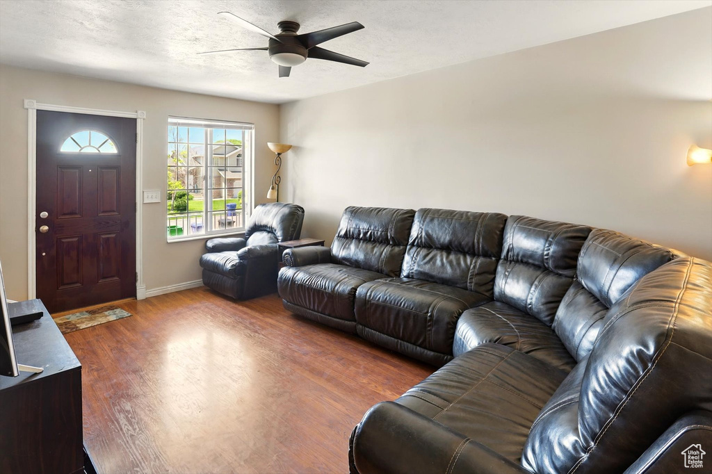 Living area with a ceiling fan, wood finished floors, and baseboards