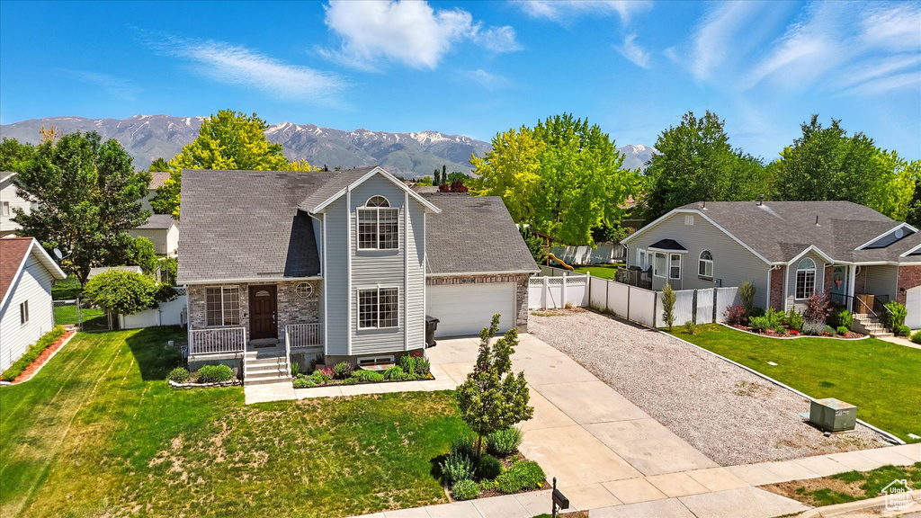 View of front facade featuring driveway, a mountain view, an attached garage, and stone siding