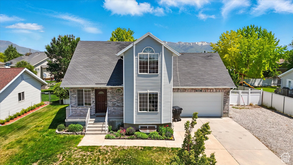 View of front of house featuring covered porch, driveway, a mountain view, an attached garage, and stone siding