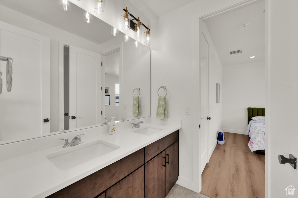 Bathroom featuring double vanity, baseboards, wood finished floors, and ensuite bathroom