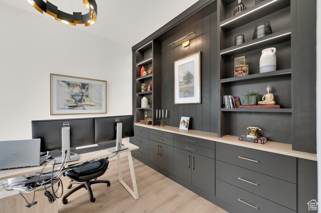 Home office with light wood-type flooring and built in features