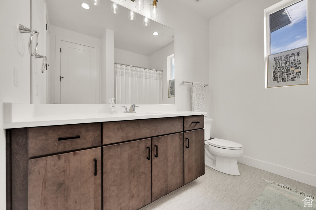 Bathroom featuring plenty of natural light, vanity, toilet, baseboards, and recessed lighting