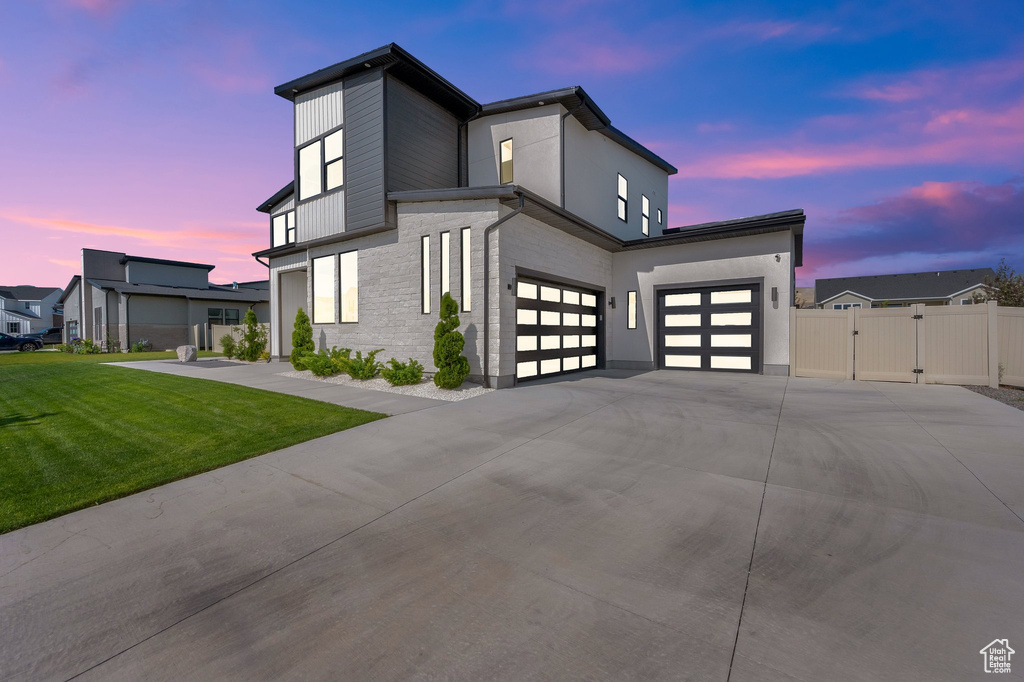View of front facade with a gate, driveway, a garage, and brick siding