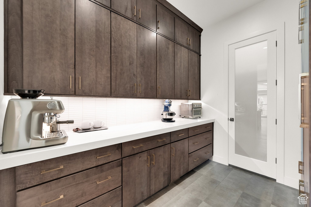 Kitchen with light countertops, dark brown cabinets, and decorative backsplash