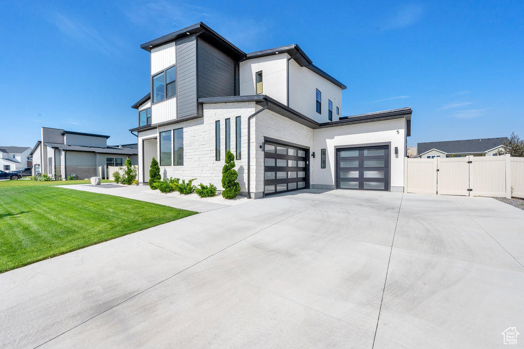 View of front of house featuring a gate, driveway, stone siding, an attached garage, and a garage