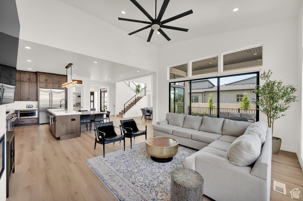 Living area with light wood finished floors, stairs, ceiling fan, and recessed lighting