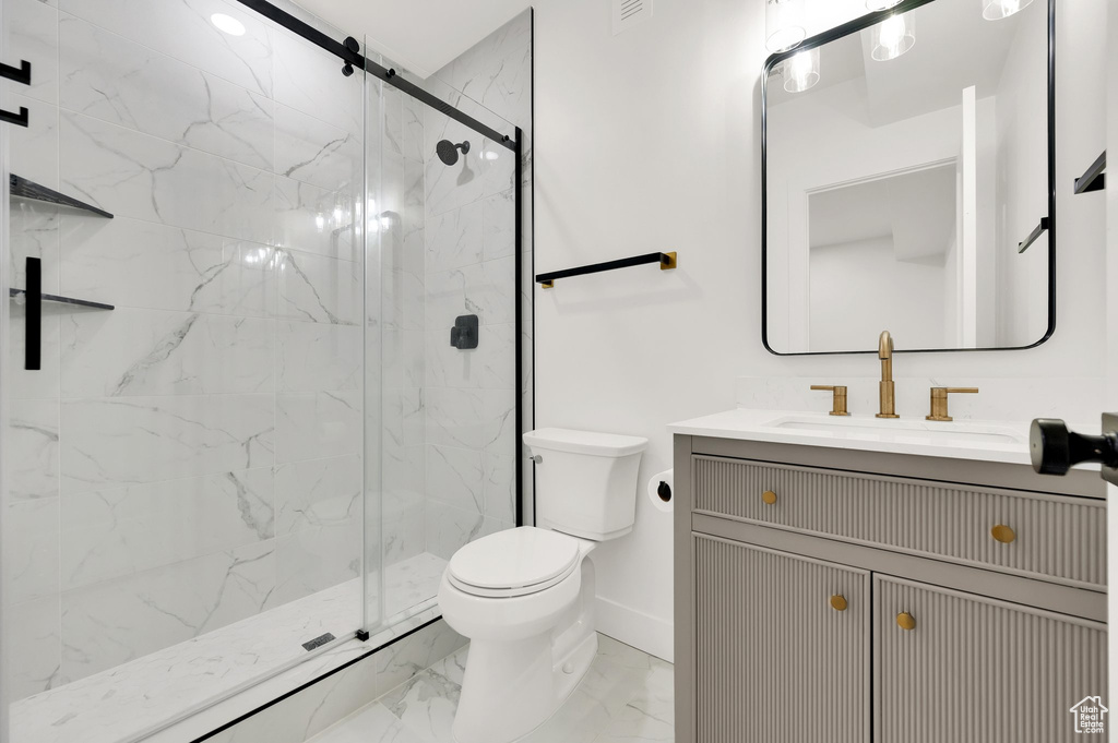 Full bathroom featuring marble finish floors, toilet, a marble finish shower, and vanity