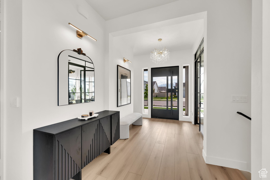 Foyer entrance featuring light wood finished floors, a chandelier, and baseboards