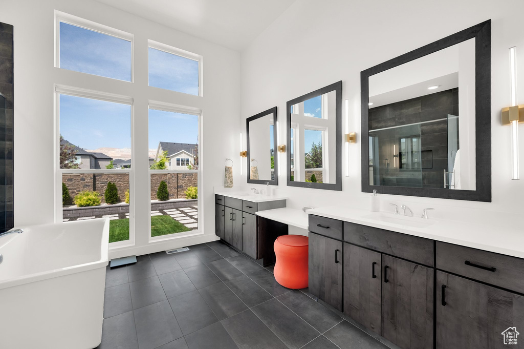 Full bathroom featuring two vanities, a stall shower, tile patterned floors, and a high ceiling