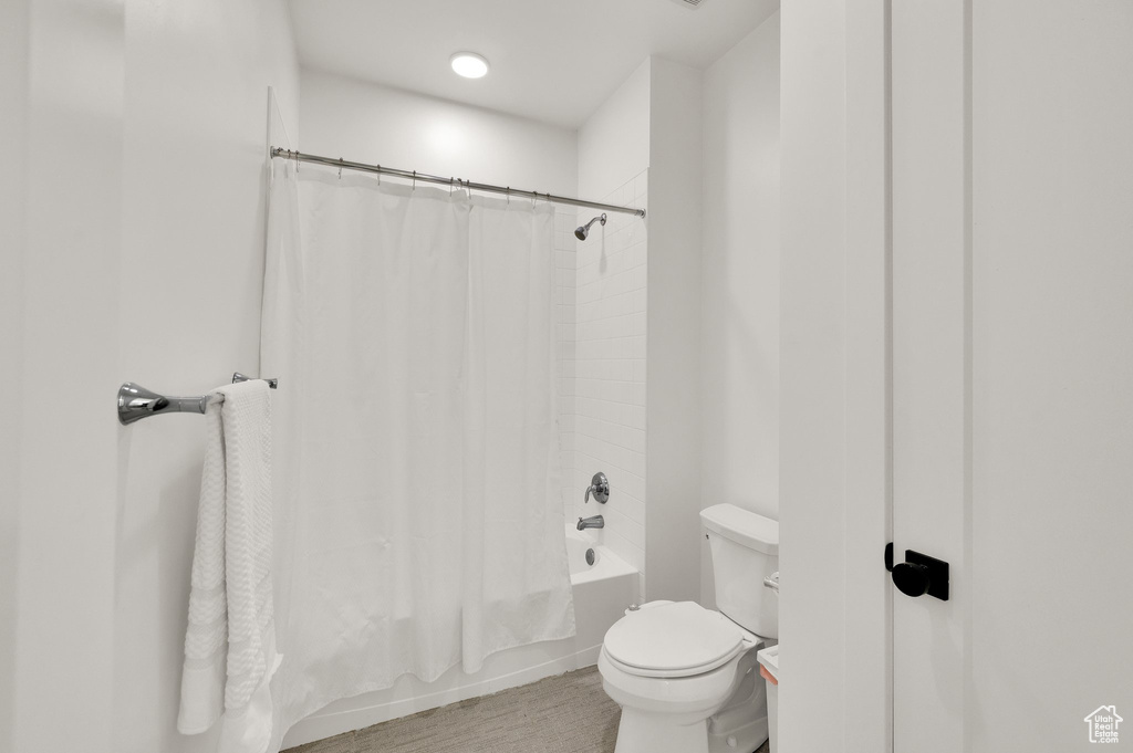 Bathroom featuring toilet and shower / bath combo with shower curtain